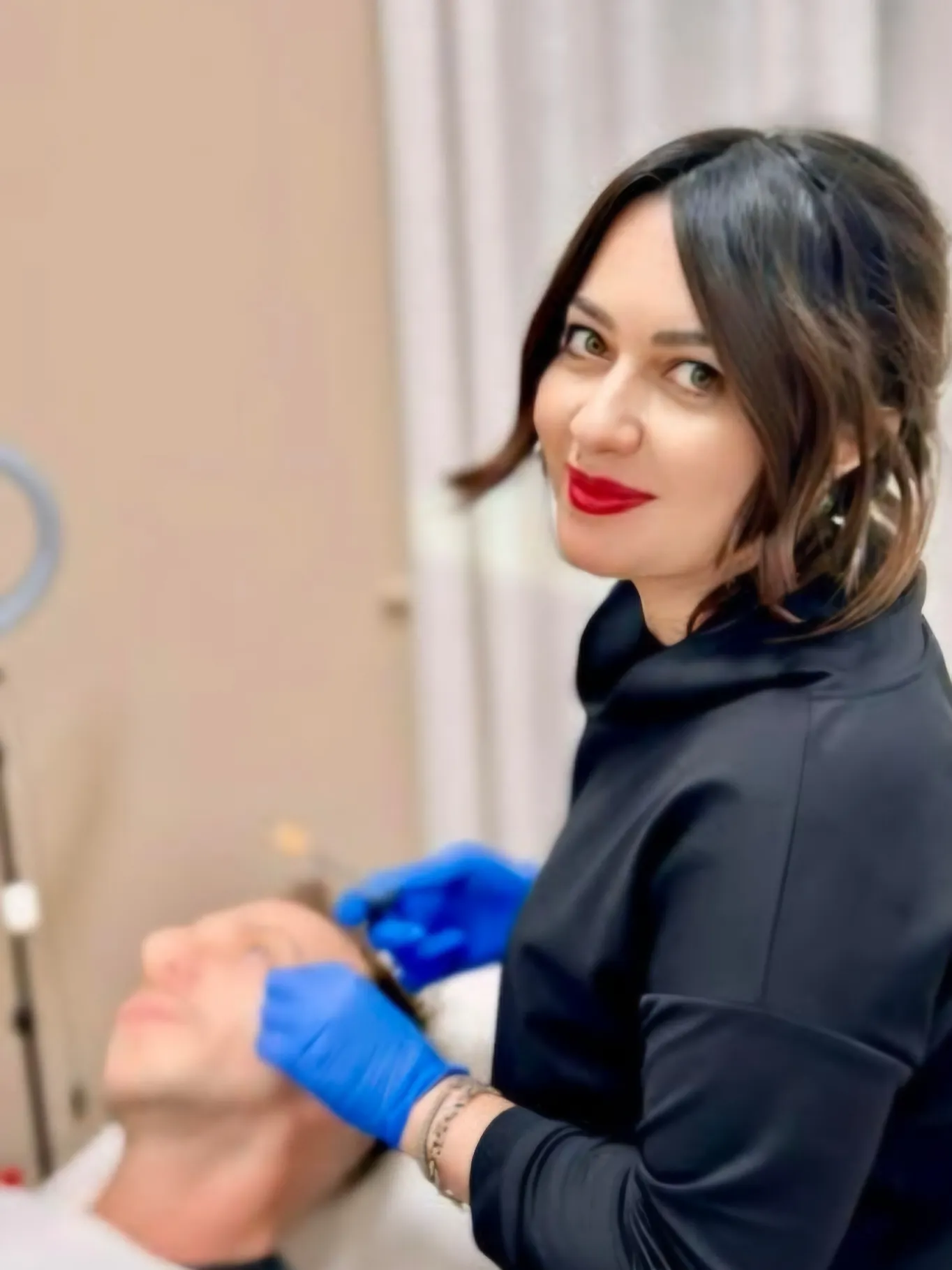 Dott.ssa Elisa Nicotra sorridente mentre esegue un trattamento al viso di un paziente